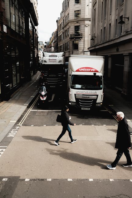 A narrow city street in Lambeth with tall, multi-storey buildings on both sides, showing a white delivery van marked 'Uniserve' parked partially on the pavement, with its rear doors closed and positio