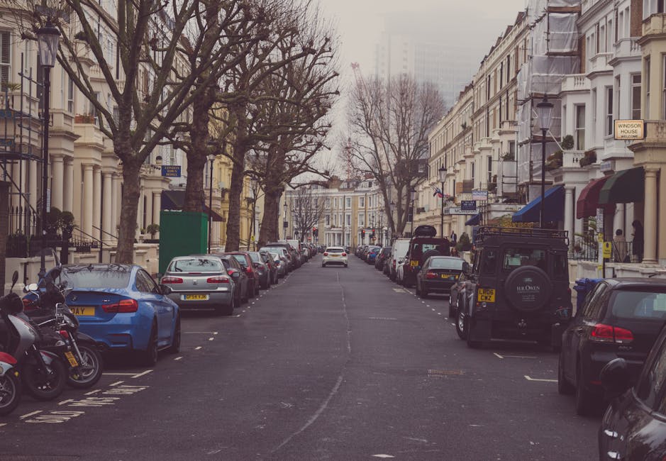A street scene near Lambeth Palace with parked cars lining both sides of the road and leafless trees along the pavement. Several vehicles, including a black Land Rover with roof racks and a spare tire